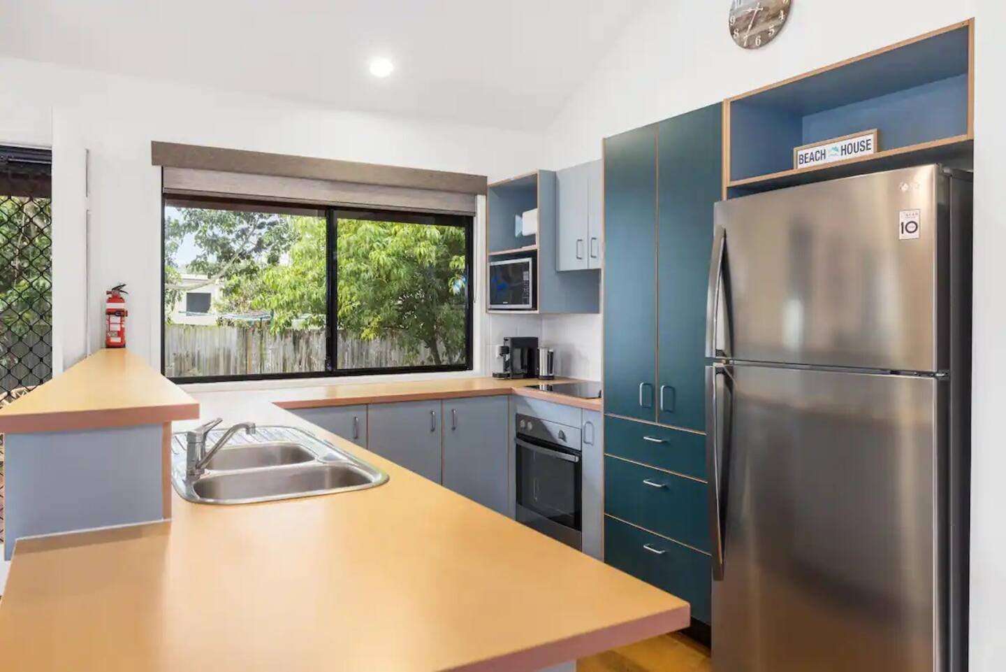 Blue kitchen cabinets and a wide window looking into the green garden